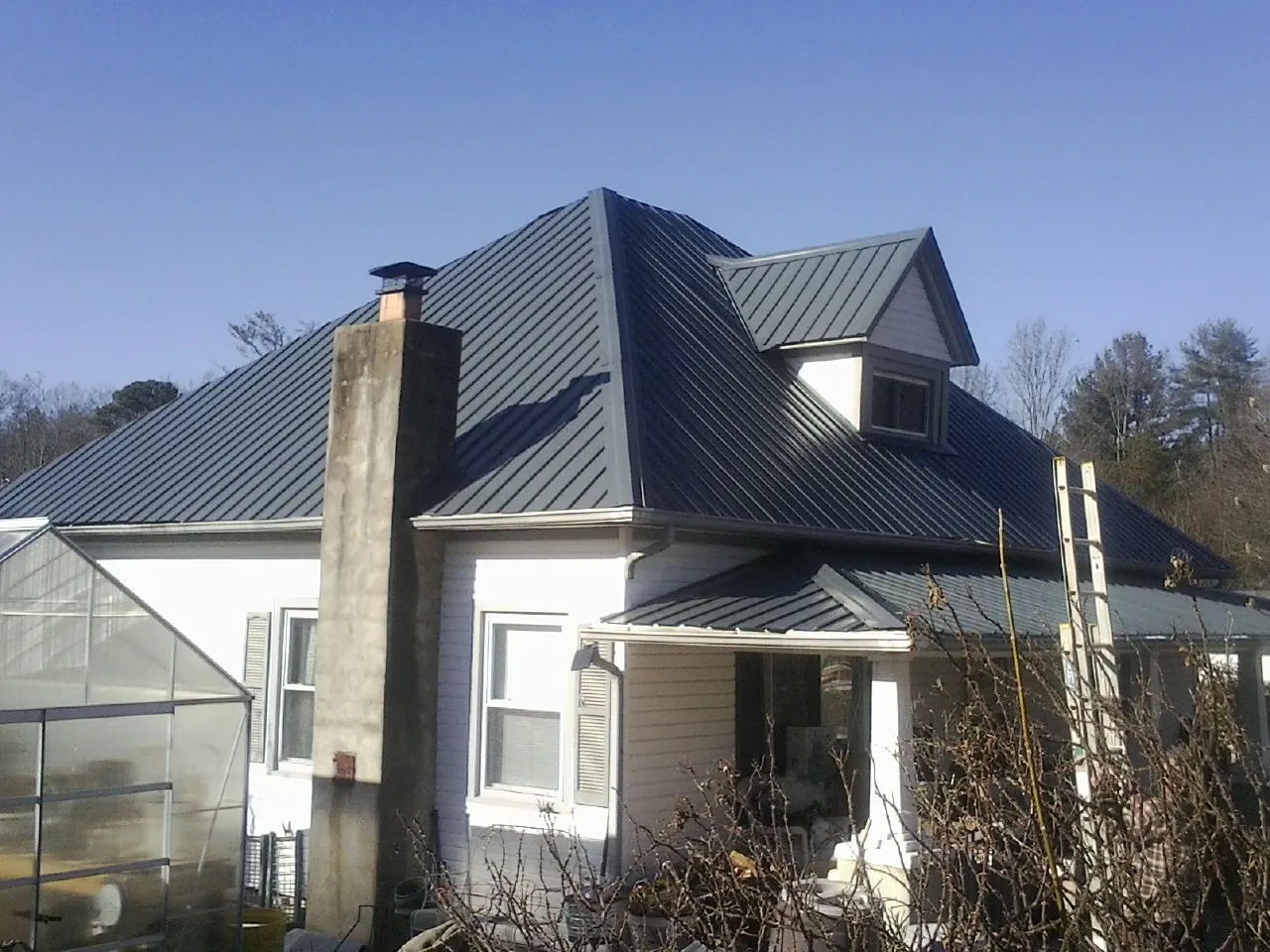 Dark blue standing seam metal roof on a white farmhouse with dormer — Slate & Tile Roof Repair by Roofing Brothers in Ridgely
