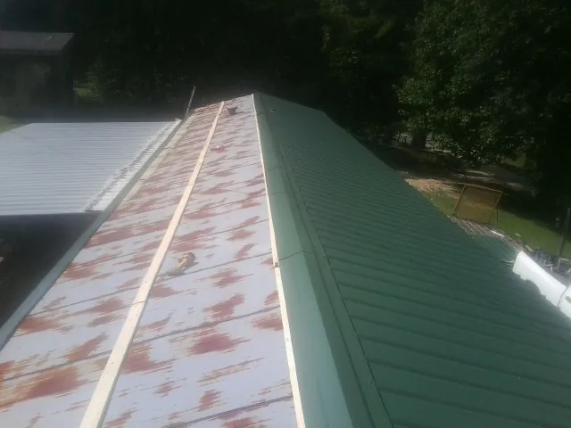 Old rusted panels beside newly installed green metal roofing — Wind Damage Roof Repair by Roofing Brothers in Ridgely