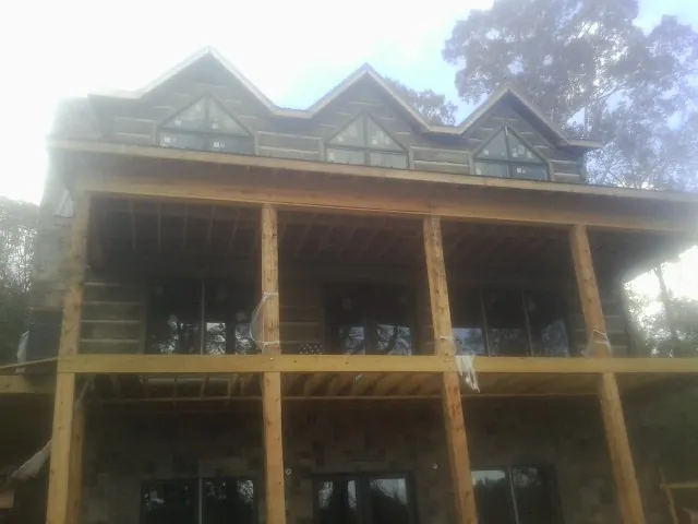 Dormers and porch framing on a large log home under construction — Roof Coating work by our crew in Ridgely