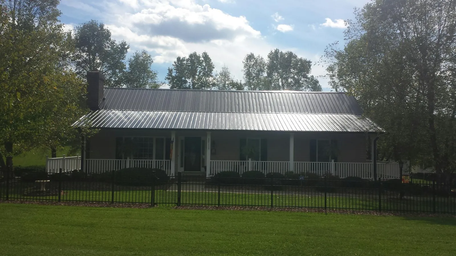 Gray metal roof on a brick ranch with a full width front porch — Gutter Guard Installation work by our crew in Ridgely