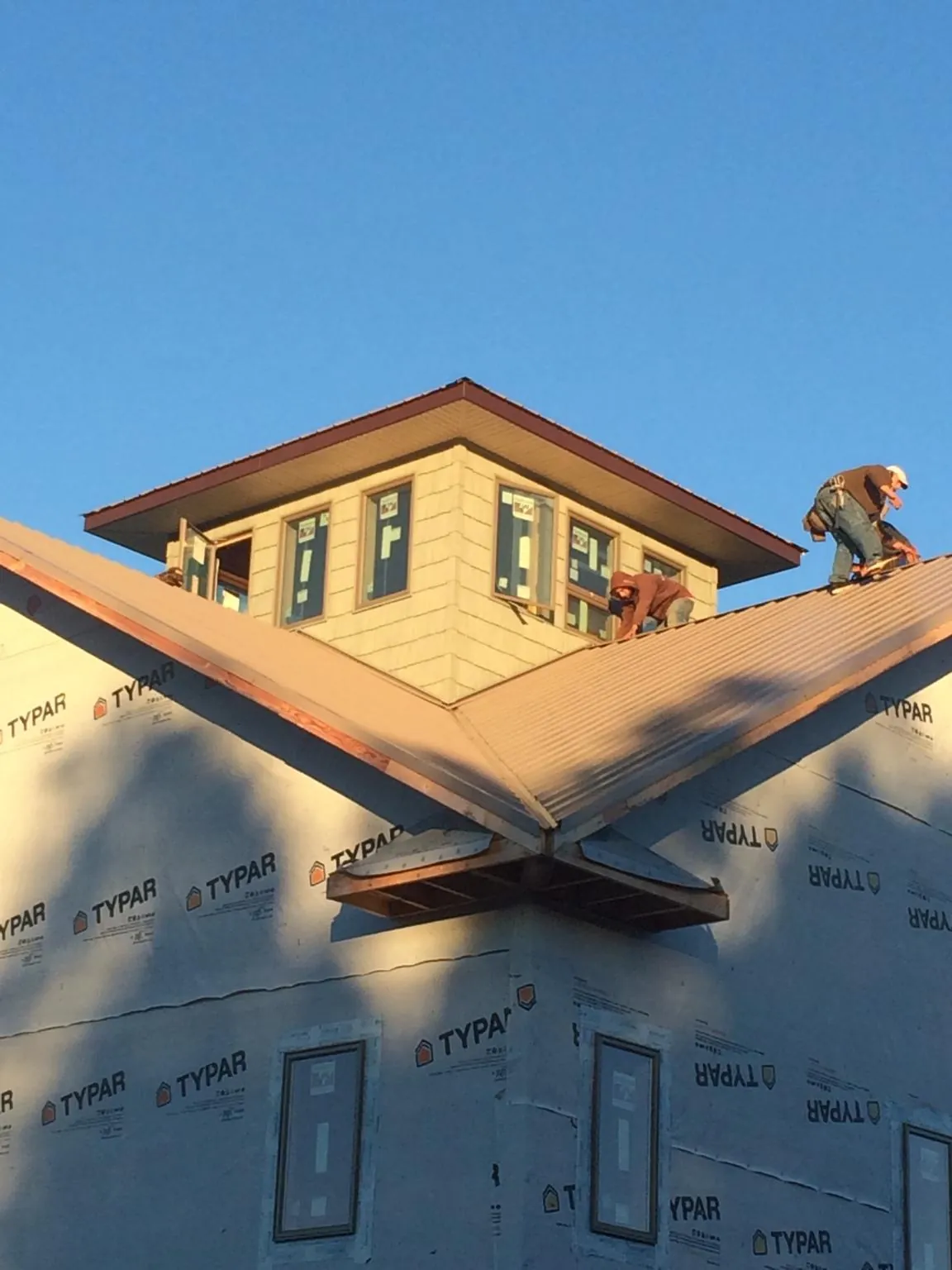 Roofers working around a rooftop cupola on a new metal roof at sunset — Roof Waterproofing in Ridgely by Roofing Brothers